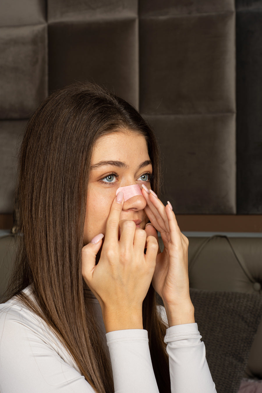 Women uses pink SleepAir nasal strip to breathe better